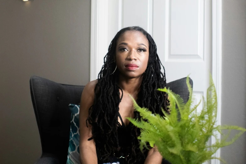 a woman sitting on a chair with a potted plant in front of her