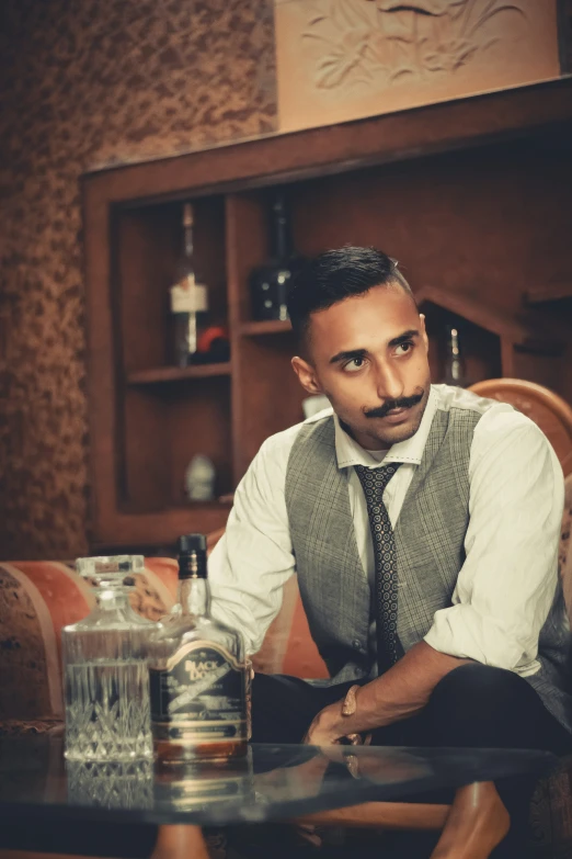 a man sitting in a chair with bottles on top of a table