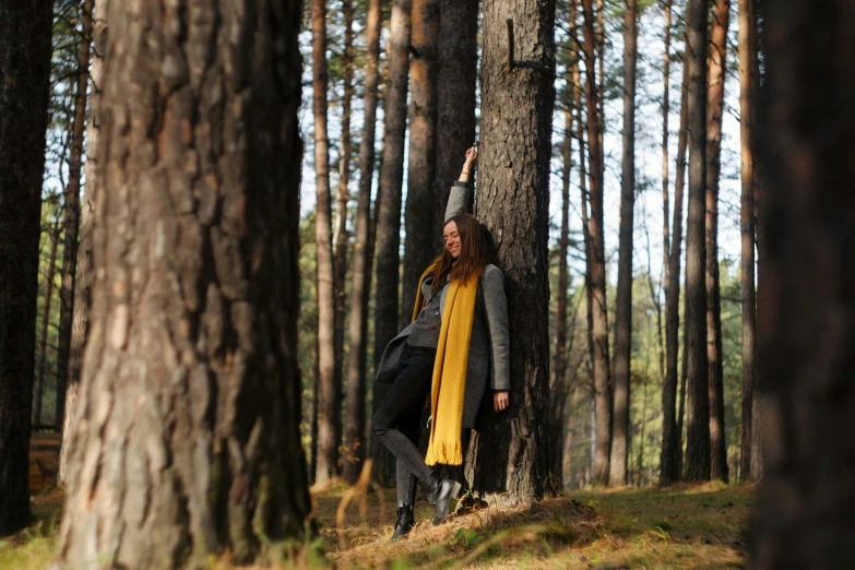 a woman standing by a tree in the woods