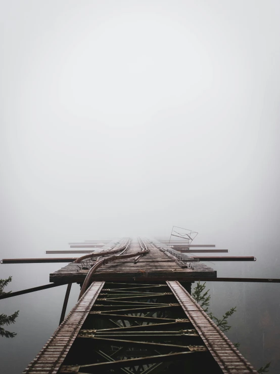 a very tall wooden bridge on a misty day