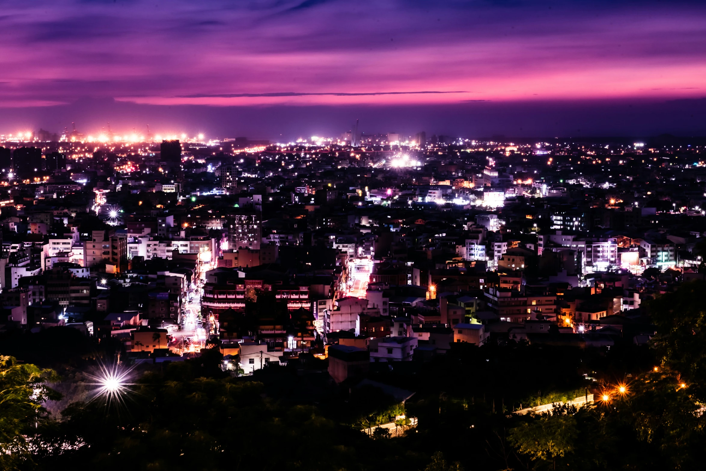 a view of a city in the night from the top of a hill