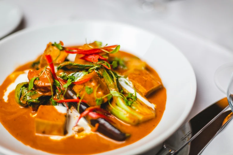 a white bowl full of food with silver utensils