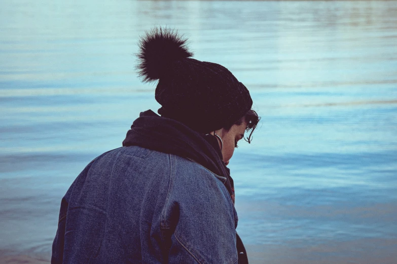 a person standing next to the water wearing a beanie