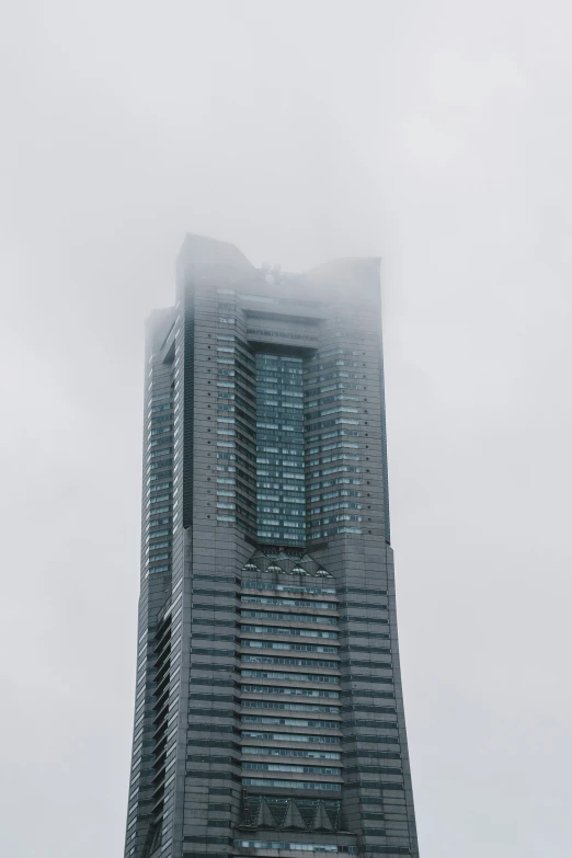 a tall building stands in the fog with a clock on top