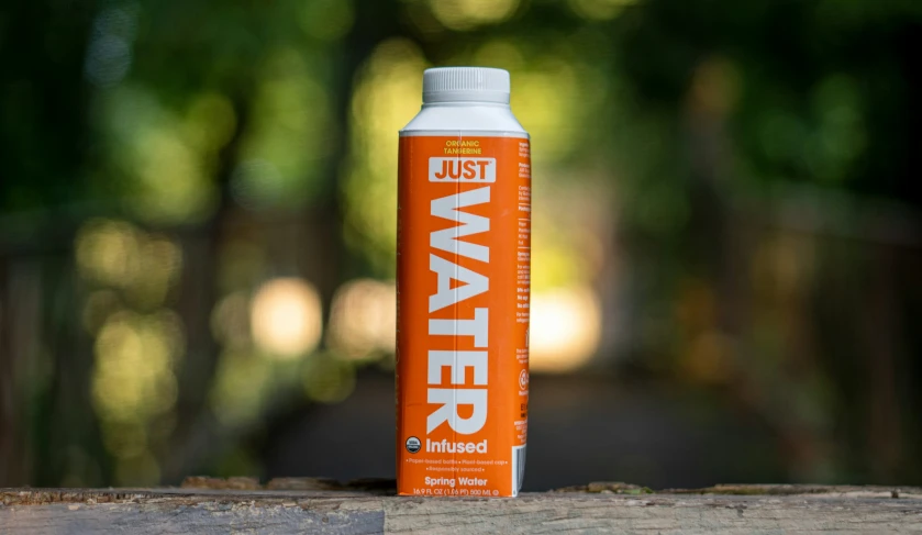 a orange bottle that says just water next to a wood table