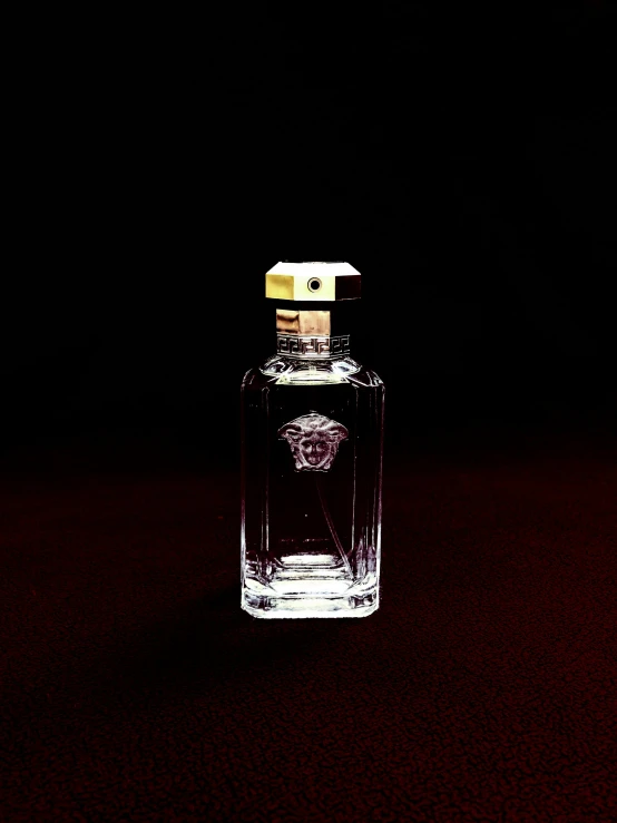 an empty glass bottle of perfume on a dark surface