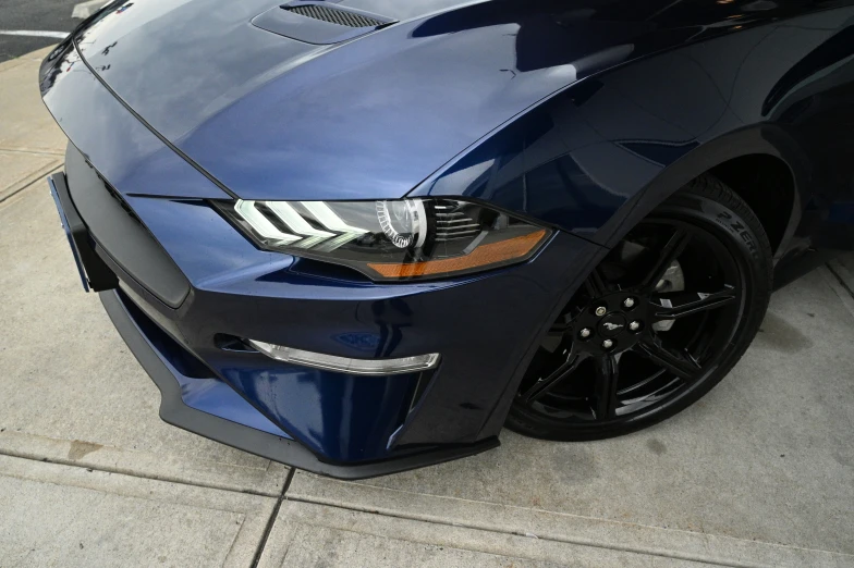 the front end of a blue sports car parked on the side of the street