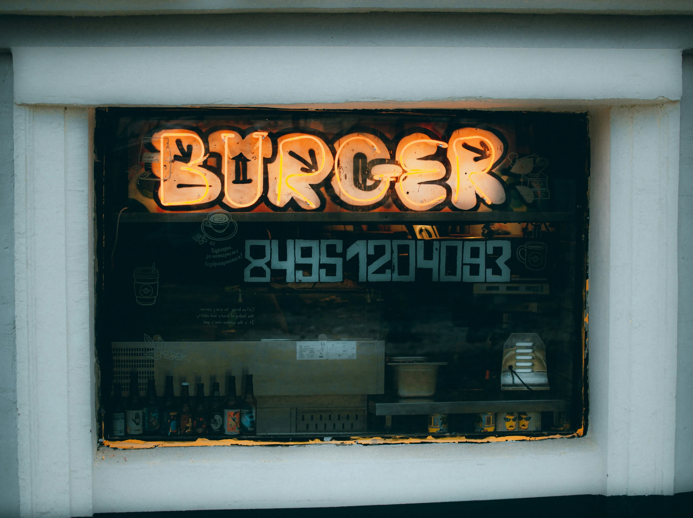 a storefront with a window lit up that reads burger