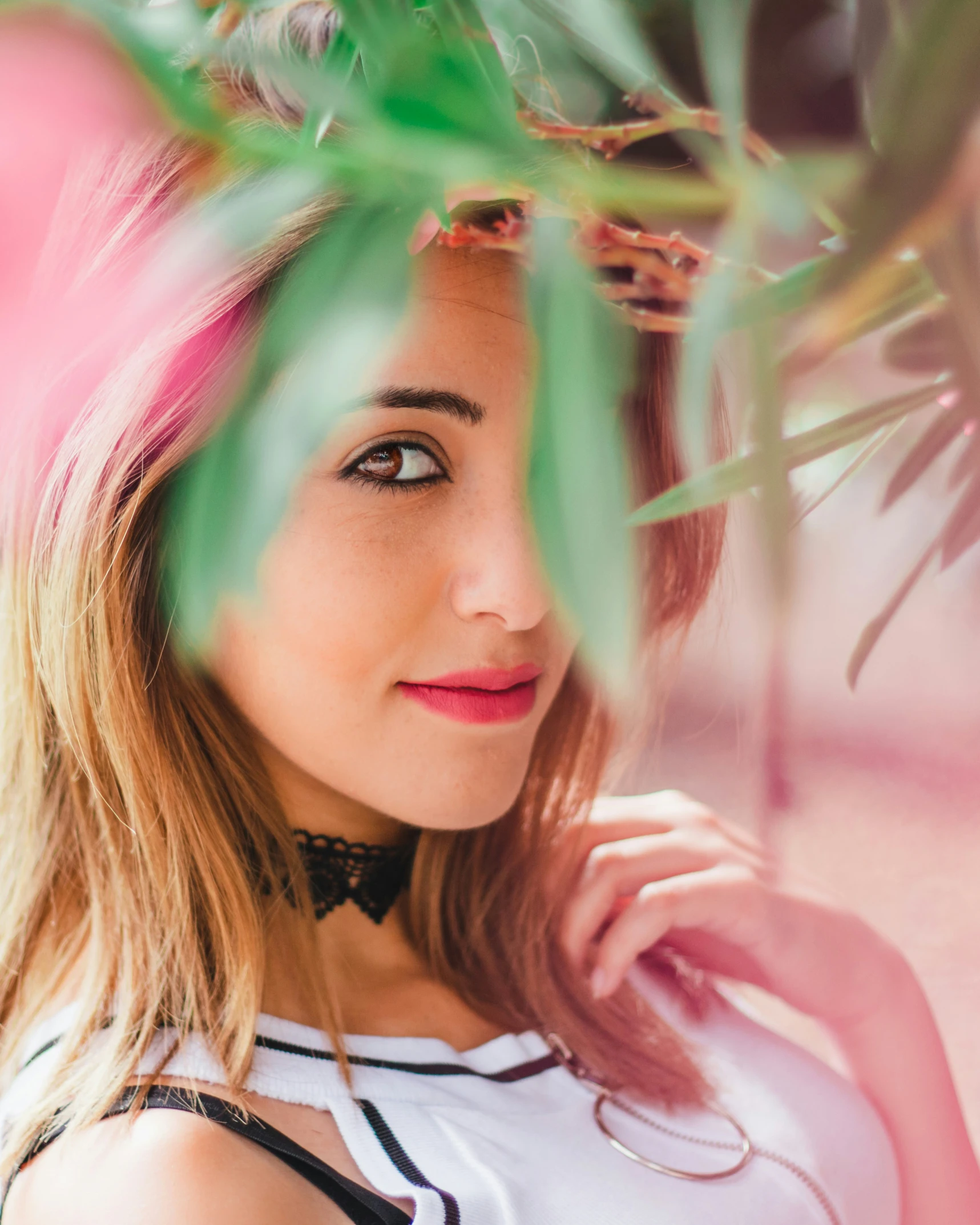 young woman posing next to a plant with green leaves