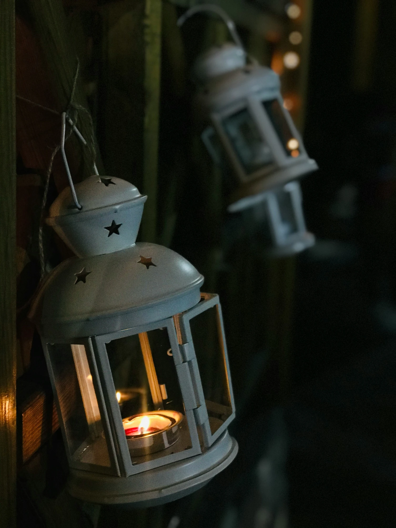 two lanterns hanging from strings with one lit inside