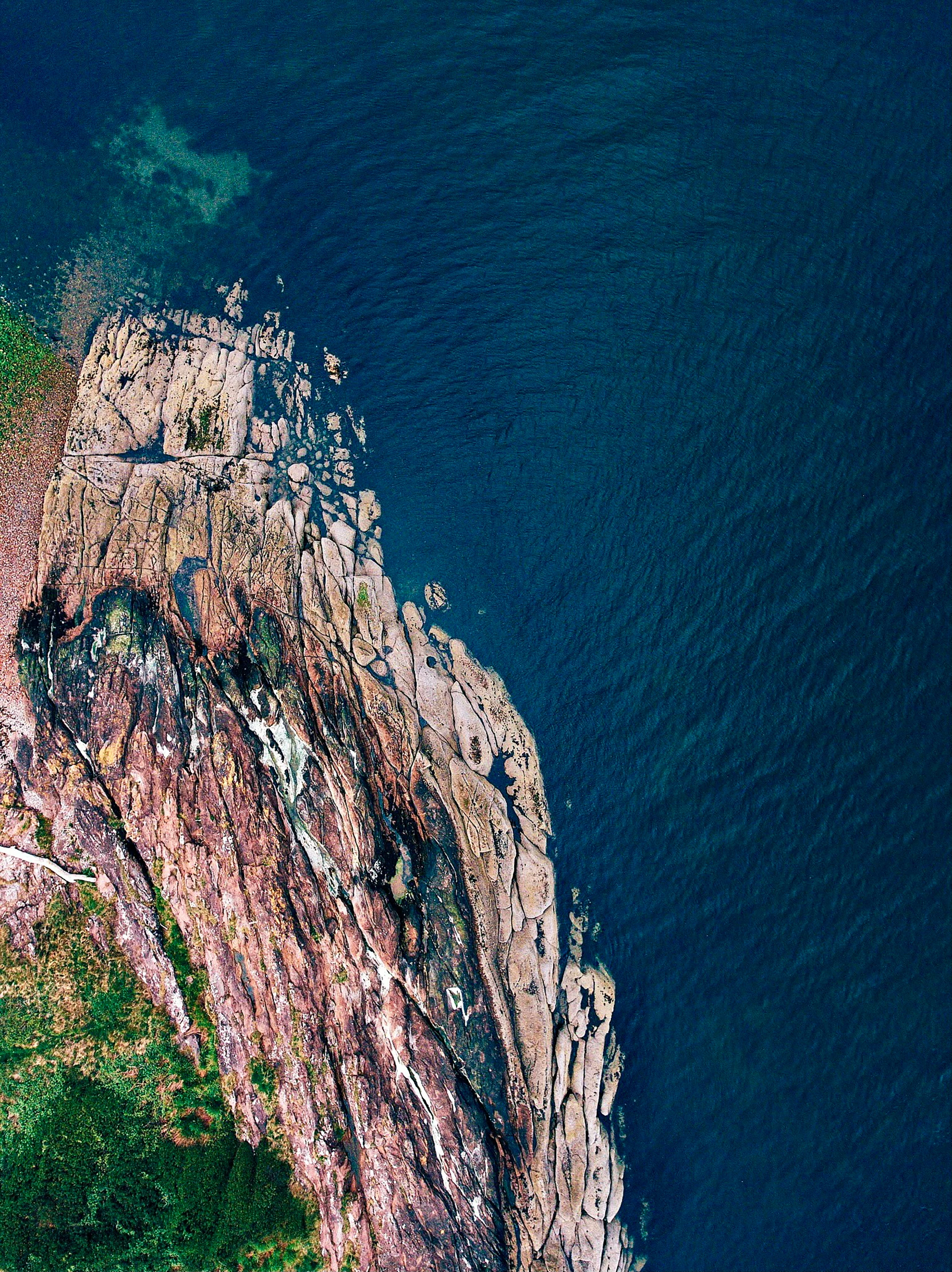 there is a large rock cliff on the edge of the ocean