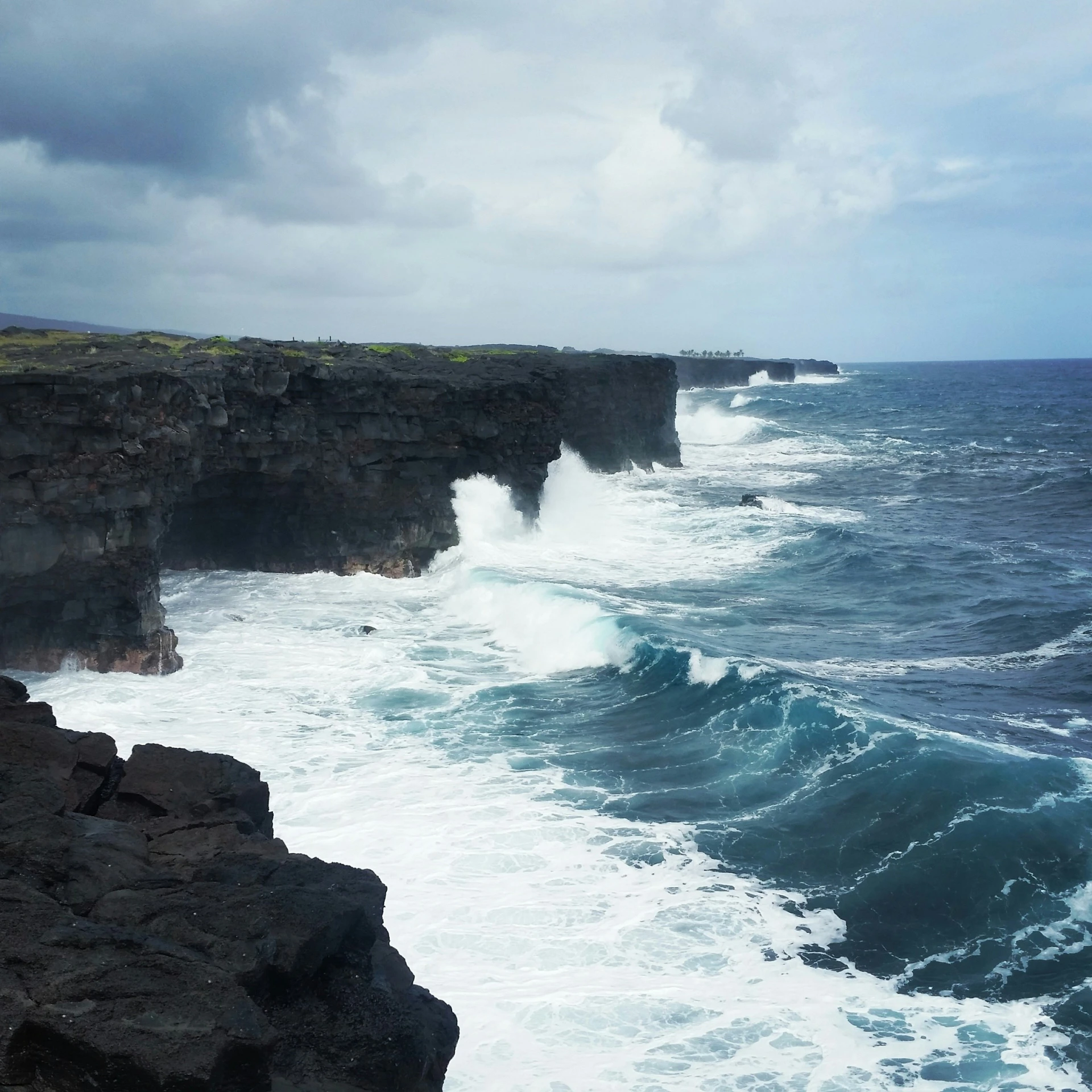 the ocean near some rocks by the cliff