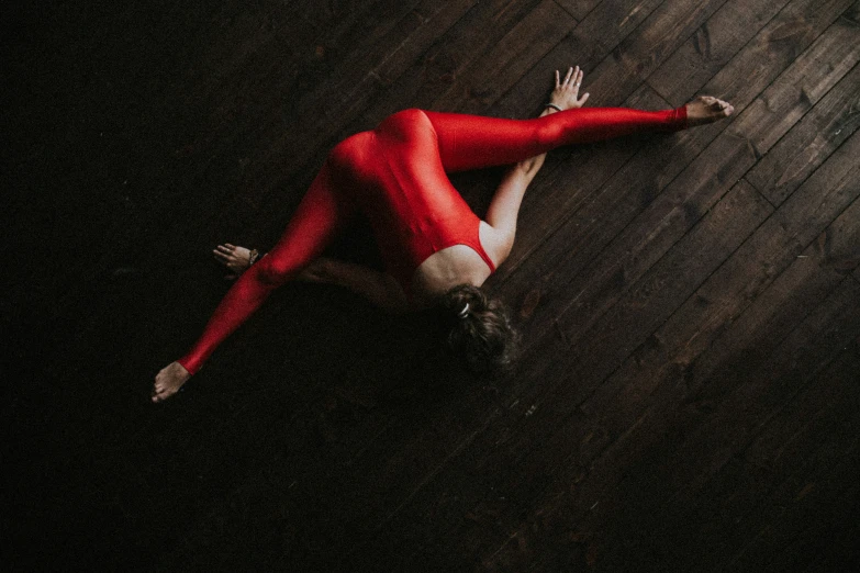 a woman is in red body suit on the floor
