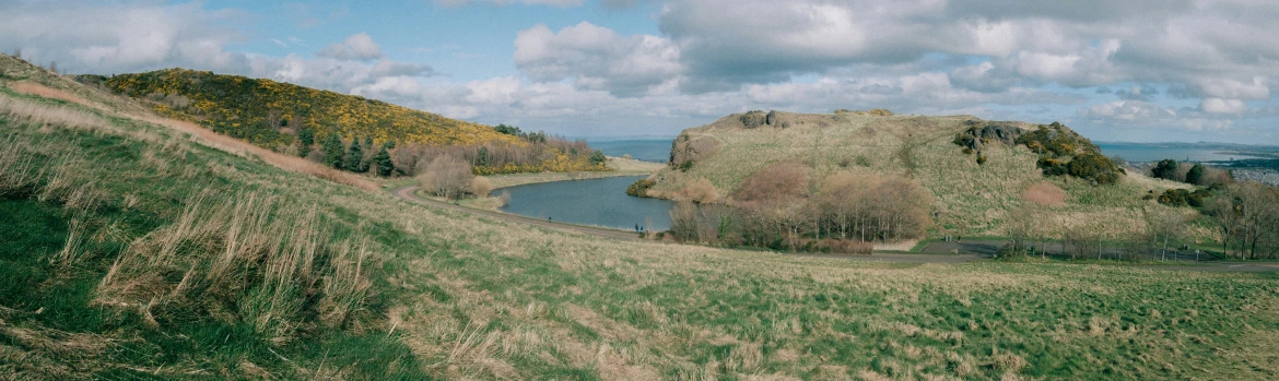 view of a lake in the middle of a grassy hillside