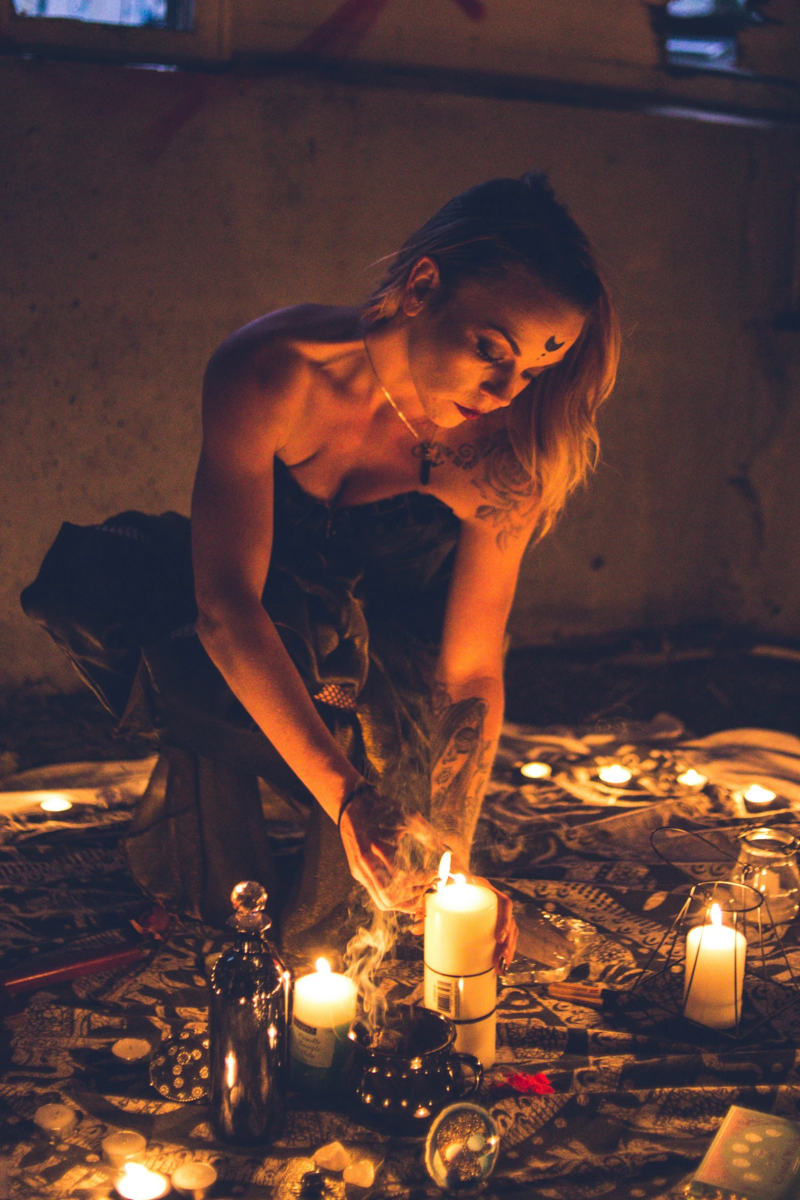 a shirtless woman bending over some candles