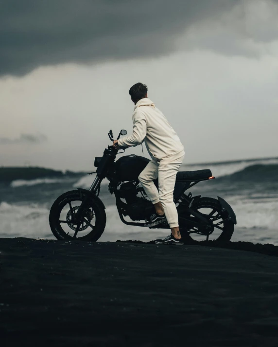 a man on a motorbike overlooking the ocean under stormy skies