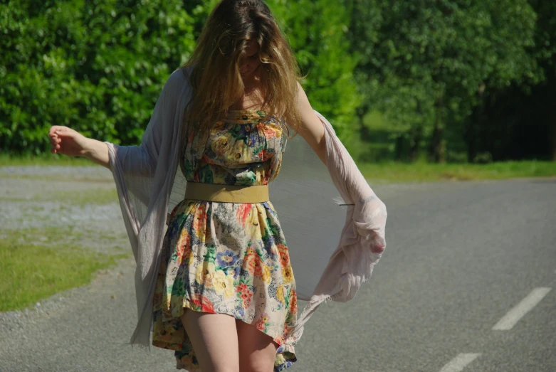 a woman with long hair walking in the middle of a road