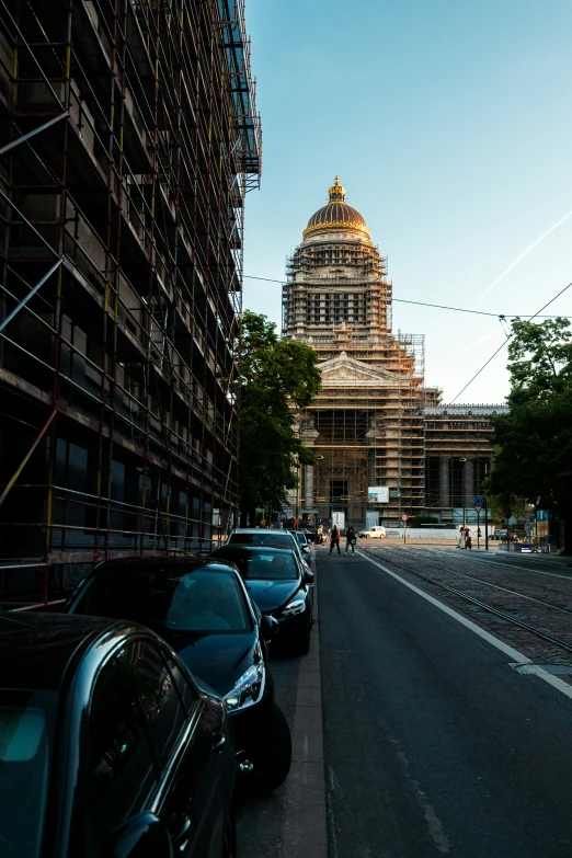 an old clock tower sits in the background behind cars parked in front of a sidewalk