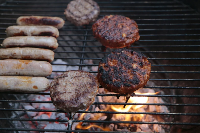 hamburgers and  dogs cooking on an outdoor grill