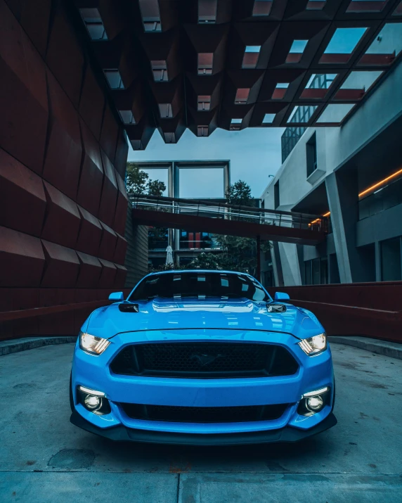 a blue mustang sits parked in an open area