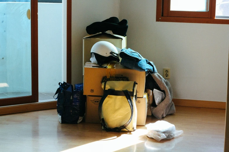 bags and shoes are stacked on a floor near the doorway