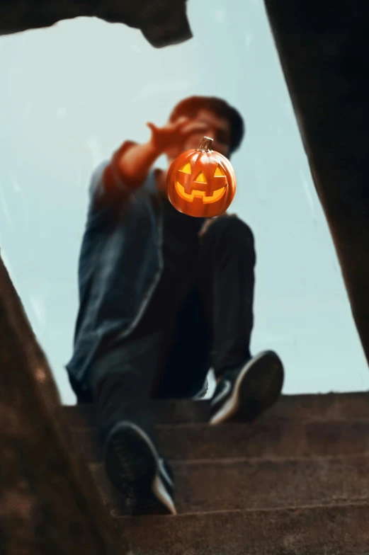 a man who is sitting down holding a trick pumpkin