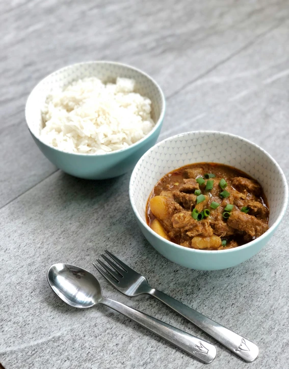 a plate with a silver spoon and bowl filled with rice