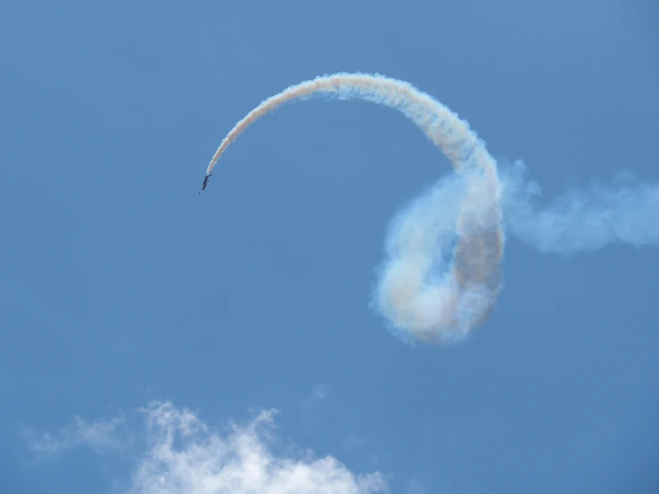 a jet making a large trail of smoke through the sky