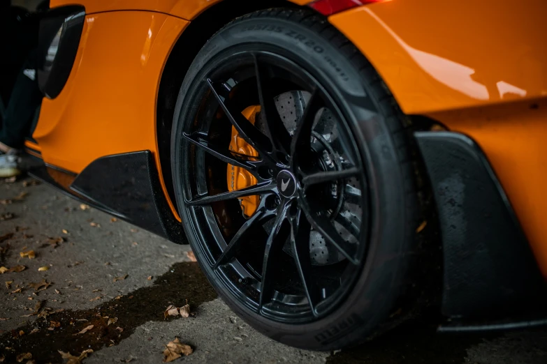 a close up of the wheels on an orange sports car