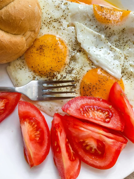 eggs, tomatoes and bread on a plate with a fork