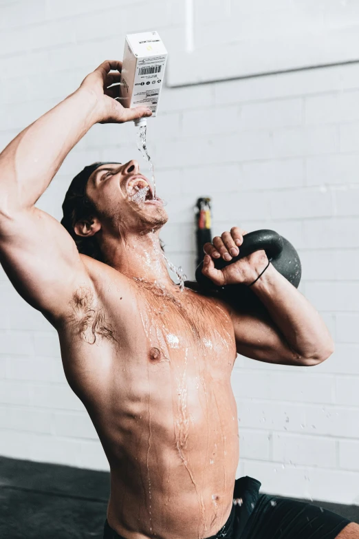 shirtless male exercising while lifting a kettle