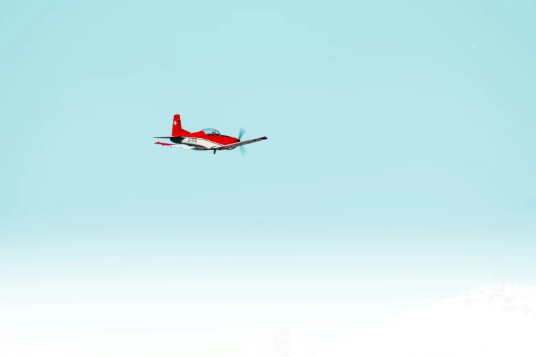 a small red airplane flying in the air