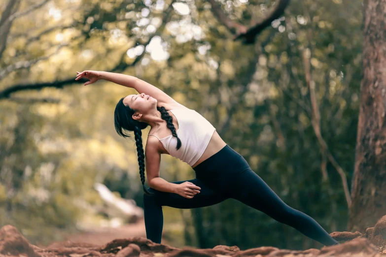 a woman is doing yoga in a forest