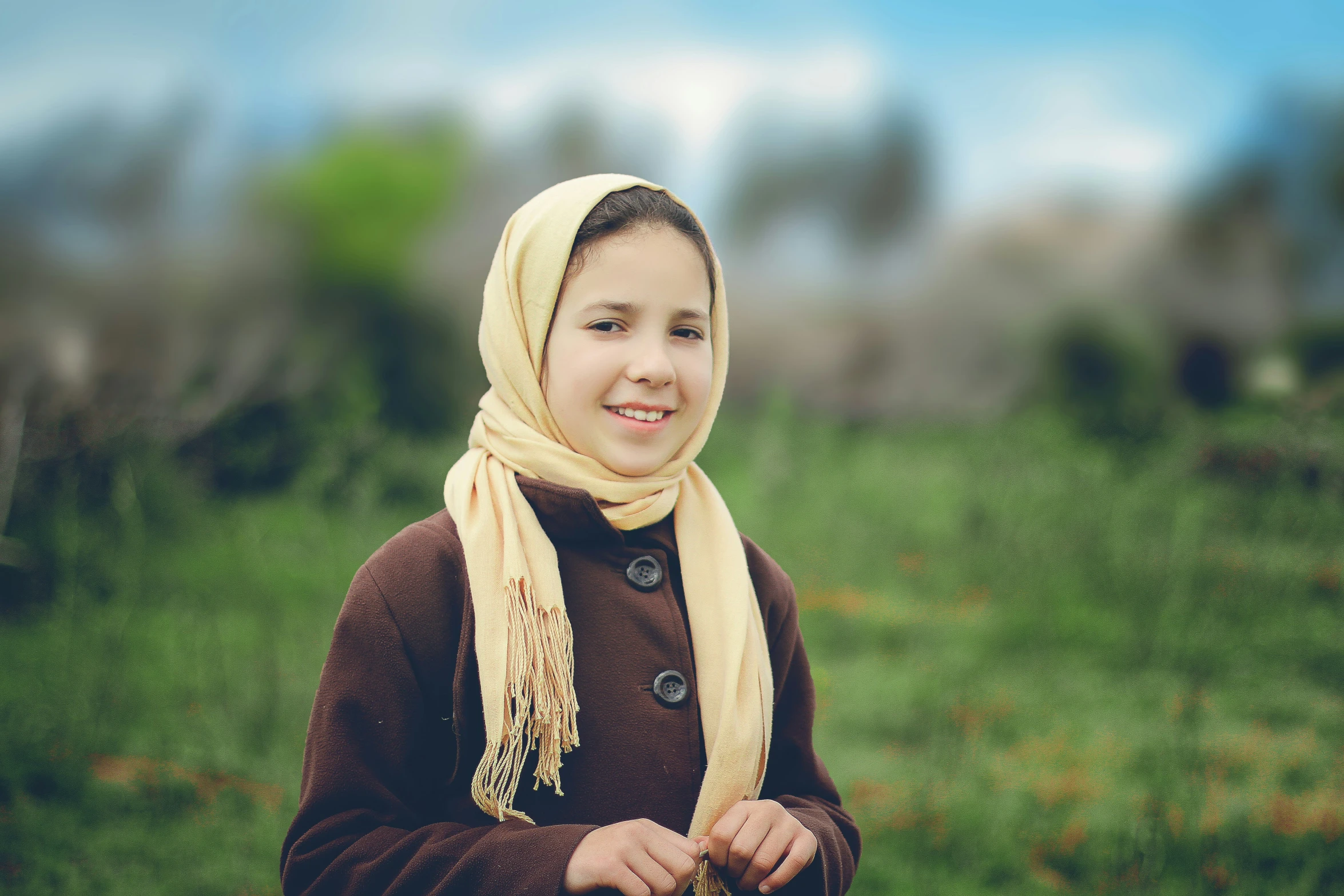 a child in a brown jacket and scarf