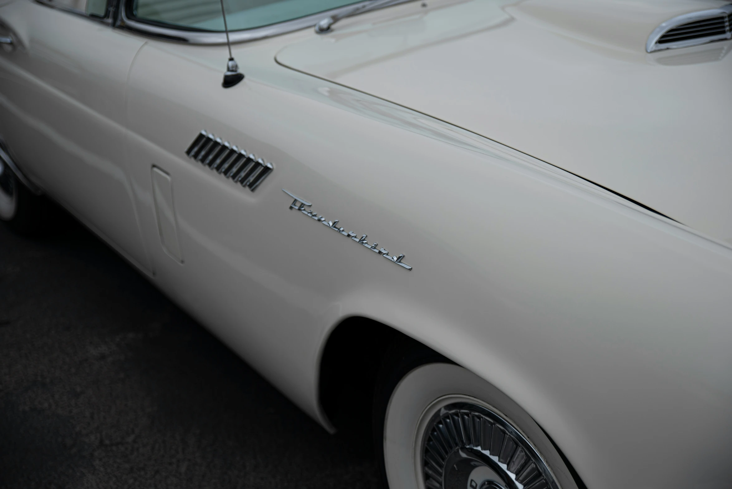 an old white car parked on the side of the road