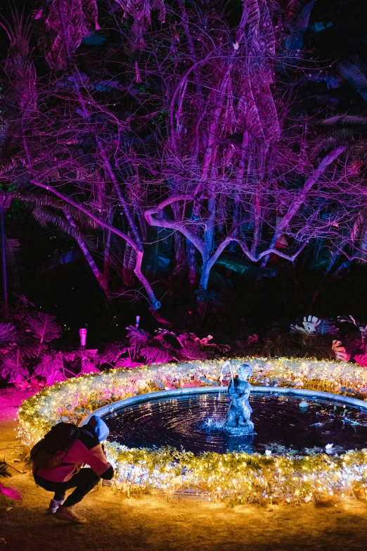 a man standing in the middle of a pond with lights