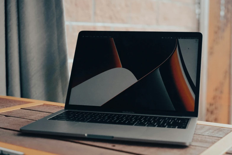 the black macbook air is on the table next to the window