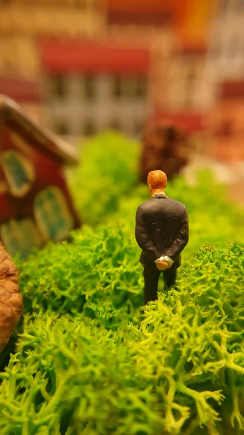 a small toy man is standing in some moss