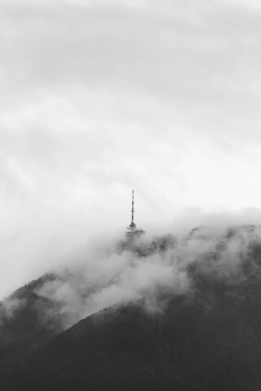 some clouds hovering near the top of a mountain