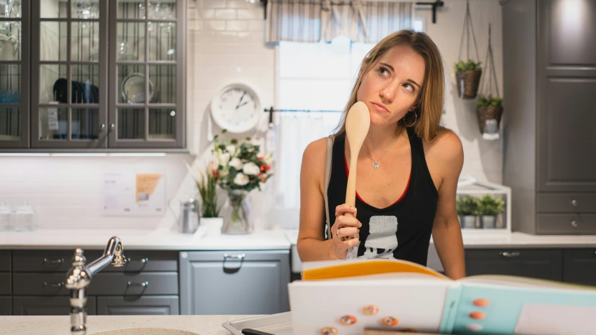 a woman is holding a whisk while standing in the kitchen