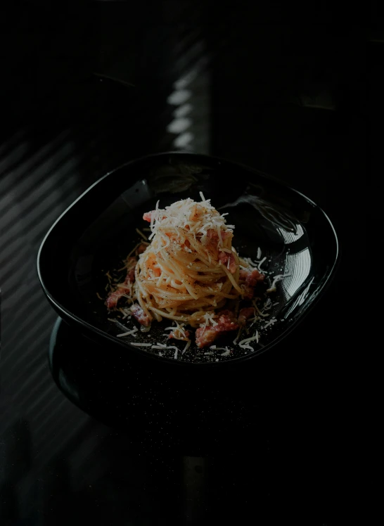 a pasta dish being eaten on a black plate