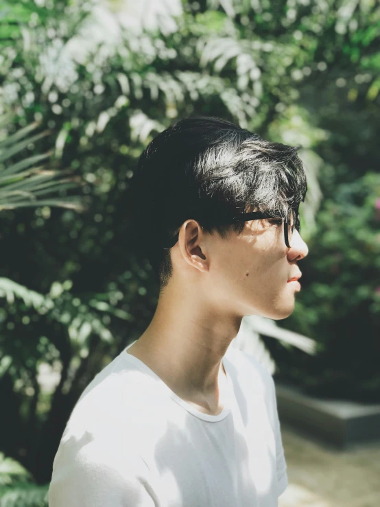 a person wearing sunglasses and a white shirt in a tree forest