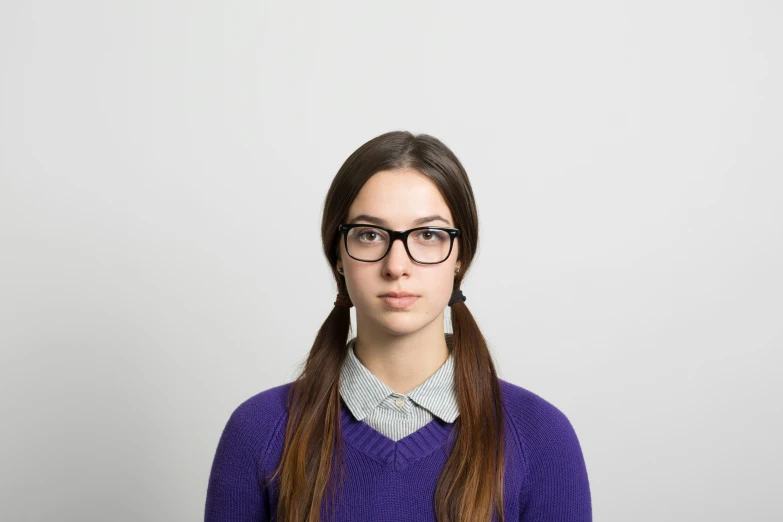 a girl wearing glasses and a sweater looking down