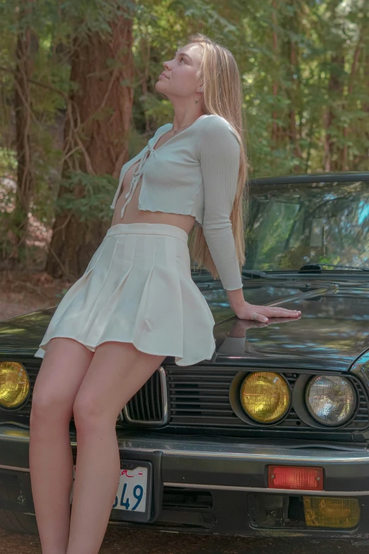 a young woman poses in front of her car