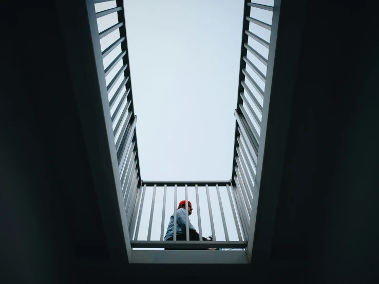 the person is standing on the top part of an escalator