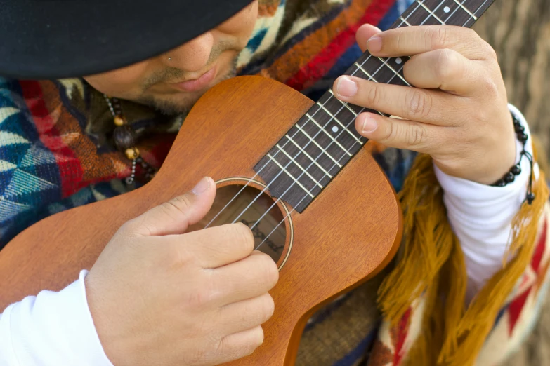 a man with a hat plays an acoustic guitar