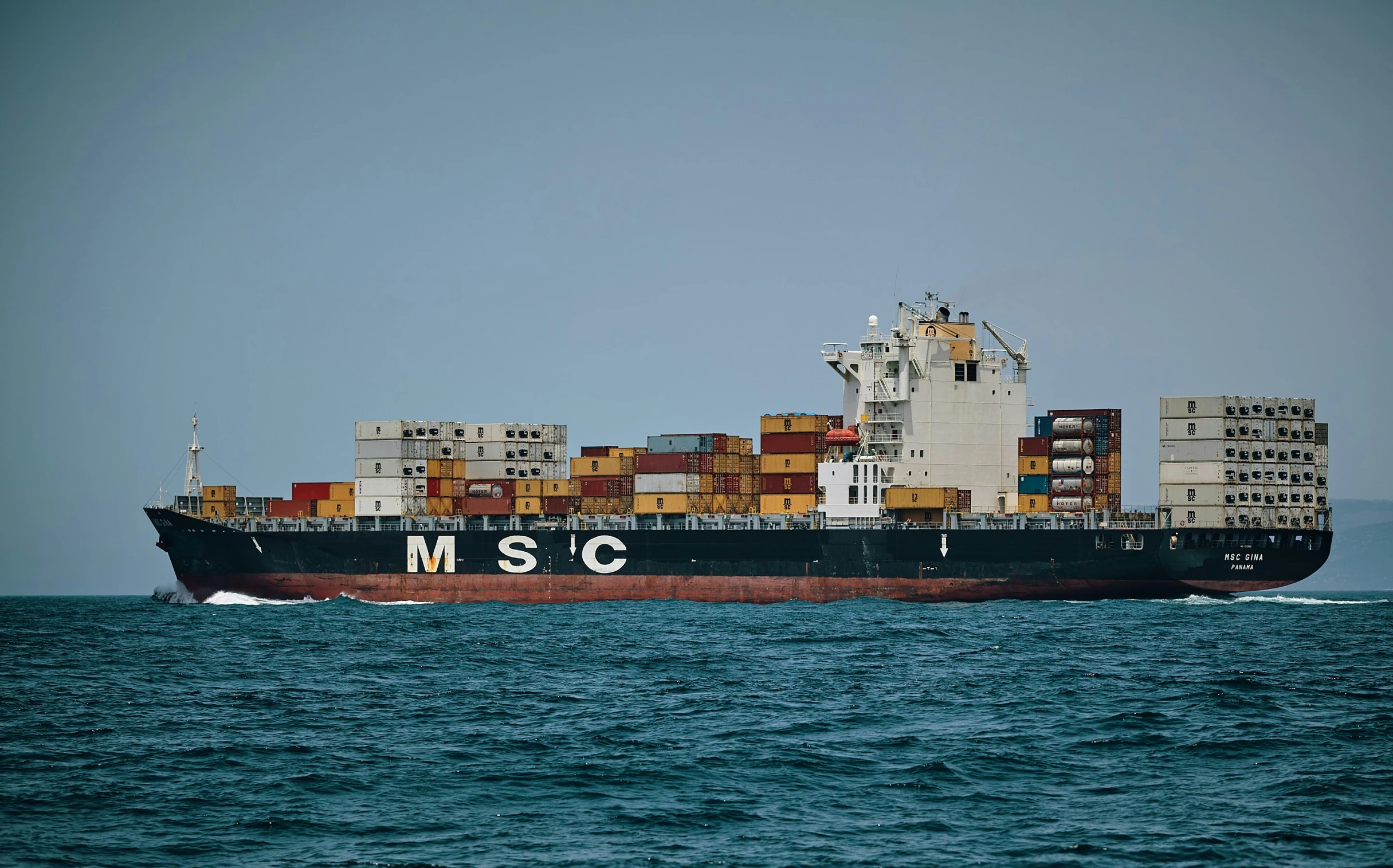 a large shipping ship in the ocean with cargo on top