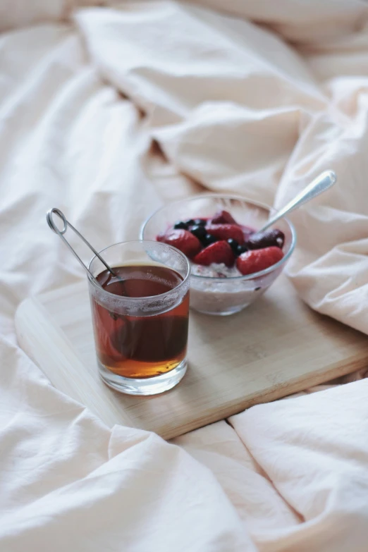 a glass of tea with a bowl full of berries in it