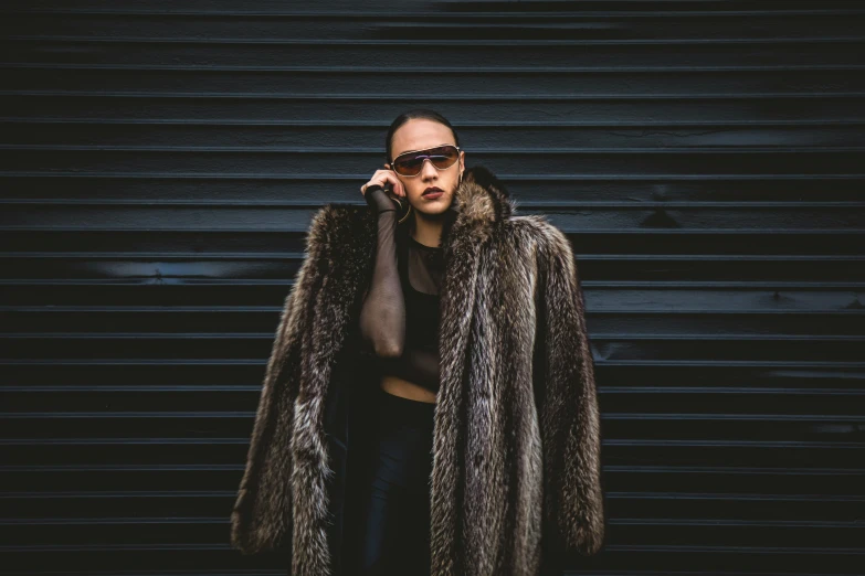 a man with dark hair, wearing a furry coat and sunglasses