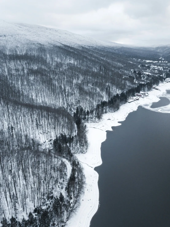 a snowy aerial view over a lake with trees